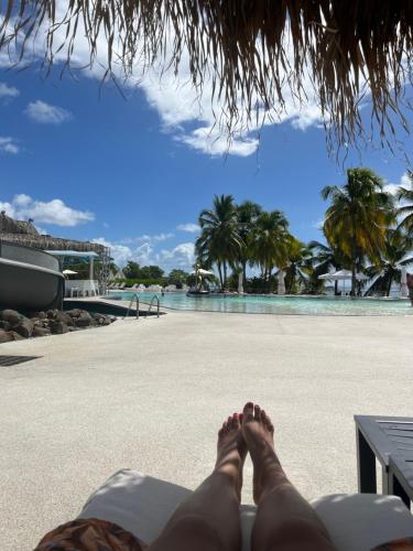 a person laying on the beach with their feet on the beach at Diamantchery - Vue mer avec Deck privatif in Le Diamant
