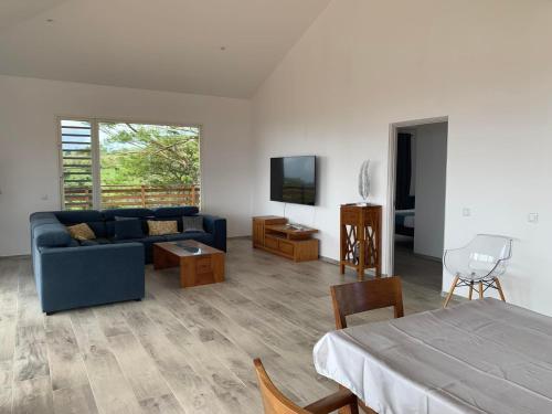 a living room with a blue couch and a tv at Puunui Lodge in Vairao