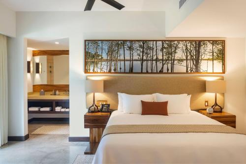 a bedroom with a large bed and a bathroom at El Mangroove Papagayo, Autograph Collection in Papagayo, Guanacaste