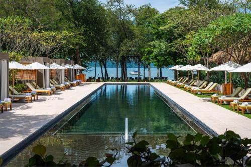 an infinity pool with lounge chairs and umbrellas at a resort at El Mangroove Papagayo, Autograph Collection in Papagayo, Guanacaste