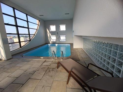 a swimming pool in a building with a large window at Apto-Flat Excelente Localização Centro-Batel - Somente Familiares in Curitiba