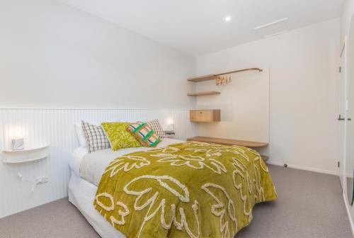 um quarto com uma cama com um cobertor amarelo em George Little em Dunedin