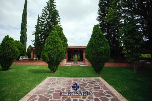 um jardim com árvores e uma casa com uma placa em Quinta El Rosario em Lagos de Moreno