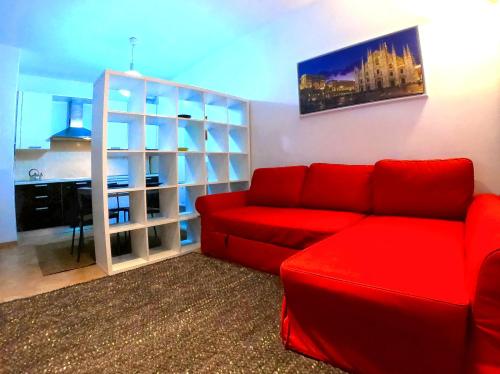 L' appartamento sul Naviglio في ميلانو: غرفة معيشة مع أريكة حمراء ومكتب