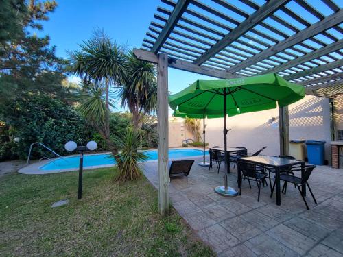 a patio with a table and umbrella next to a pool at Hotel Genoves in Piriápolis