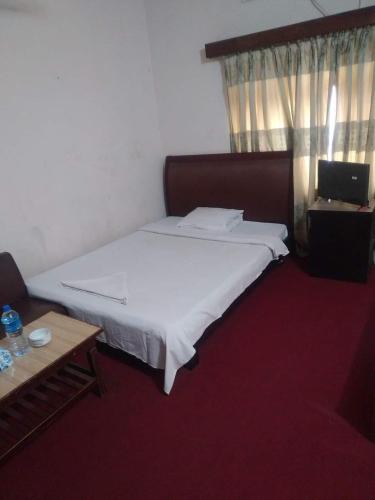 a bedroom with a large white bed and a table at Taz Garden House in Dhaka