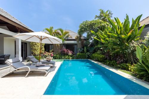 un'immagine di una piscina con due sedie e un ombrellone di Kejora Beachfront Estate Sanur - Luxurious Villa Seven Kejora a Sanur
