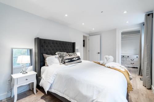 a white bedroom with a large bed and a window at lacbrome Chalet lake+Terrasse+BBQ+Hot-tub in Lac-Brome