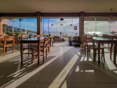 un restaurante con mesas y sillas y vistas al océano en Hotel Genoves en Piriápolis