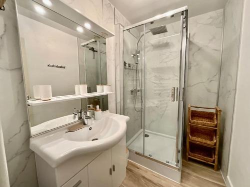 ein weißes Bad mit einem Waschbecken und einer Dusche in der Unterkunft Les Xettes, bel appartement style chalet avec vue in Gérardmer