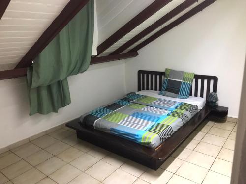 ein kleines Bett in einem Zimmer mit einer Decke in der Unterkunft SCI AZUR in Basse-Terre