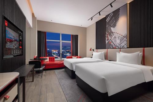 a hotel room with two beds and a tv at Radisson RED Hotel Zhuhai Gongbei Port in Zhuhai