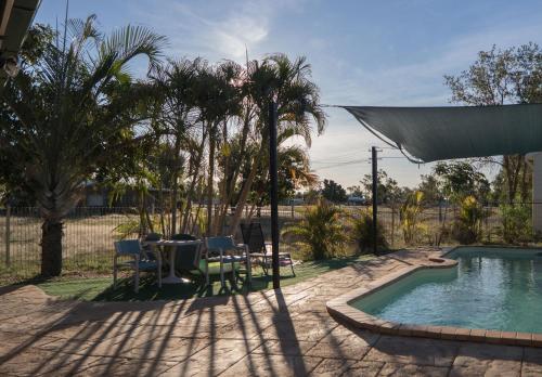 a backyard with a swimming pool with a table and chairs at Ironbark Inn in Barcaldine