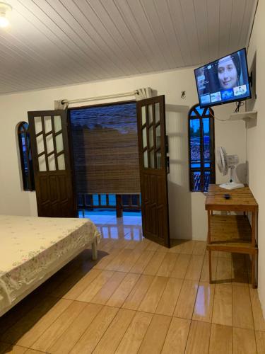 a bedroom with a bed and a flat screen tv at Planeta Verde Apartamentos in Itacaré