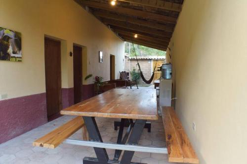 a large wooden table in a room with a kitchen at Ecolodge Guancascos, cabaña para 16 personas al pie del PN Celaque in Villa Verde