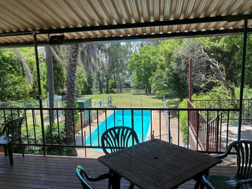 a wooden deck with a table and chairs and a pool at Bridge Motel Wellington in Wellington