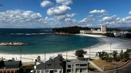 a view of a beach with the ocean and buildings at Hotel Sanrakuso in Shirahama