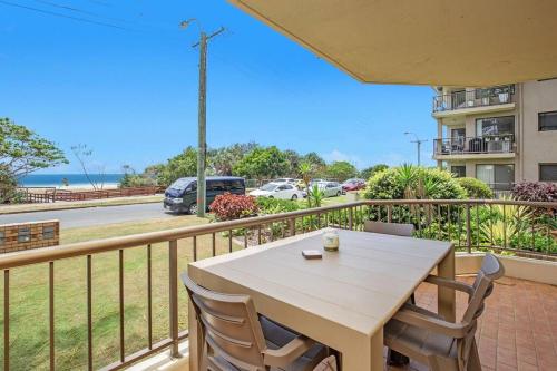 a table and chairs on a balcony with a view of a street at Absolute beachfront apartment! in Gold Coast