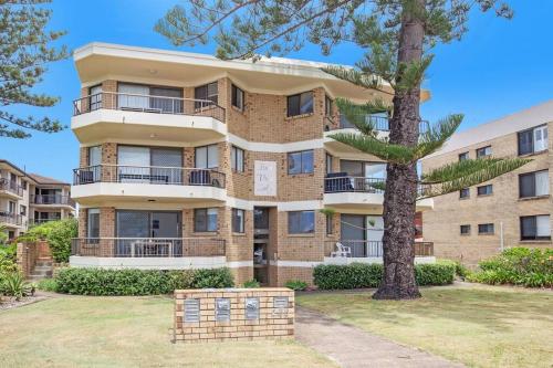 an apartment building with a tree in front of it at Absolute beachfront apartment! in Gold Coast