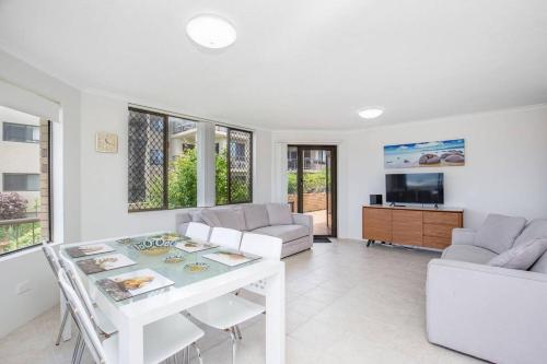 a white living room with a white table and chairs at Absolute beachfront apartment! in Gold Coast