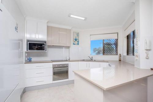 a white kitchen with white cabinets and a counter top at Absolute beachfront apartment! in Gold Coast