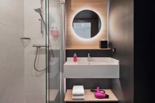 a bathroom with a sink and a shower with a mirror at Moxy Hamburg Altona in Hamburg