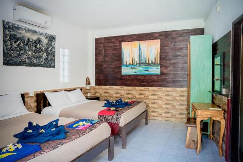 a room with two beds and a table and a desk at Oasis Lembongan in Nusa Lembongan