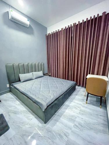 a bedroom with a bed and a chair and curtains at River Hotel 5 in Long Xuyên