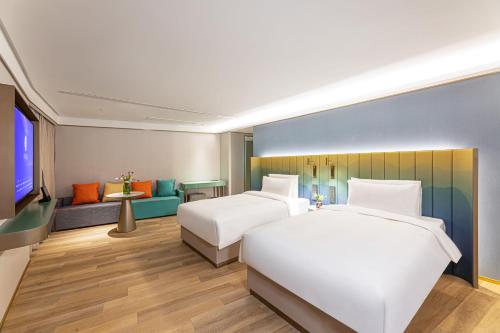 um quarto de hotel com duas camas e um sofá em Man Xin Zhangjiagang Pedestrian Street Hotel em Zhangjiagang