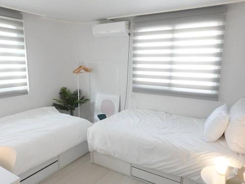 two beds in a bedroom with white walls and windows at Stay Daewha Kintex 5min Daewha Station 5min Baek Hospital 1min in Goyang
