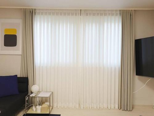 a living room with a large window with white curtains at Stay Daewha Kintex 5min Daewha Station 5min Baek Hospital 1min in Goyang