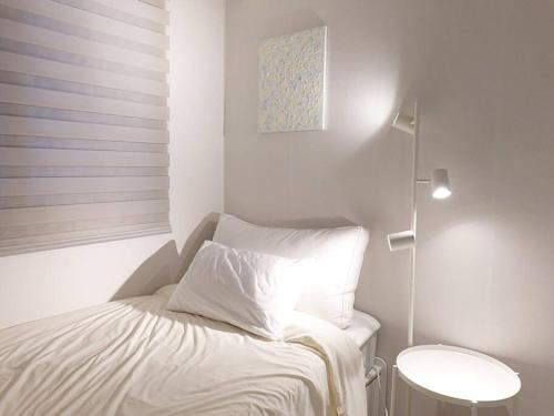 a small white bedroom with a bed and a table at Stay Daewha Kintex 5min Daewha Station 5min Baek Hospital 1min in Goyang