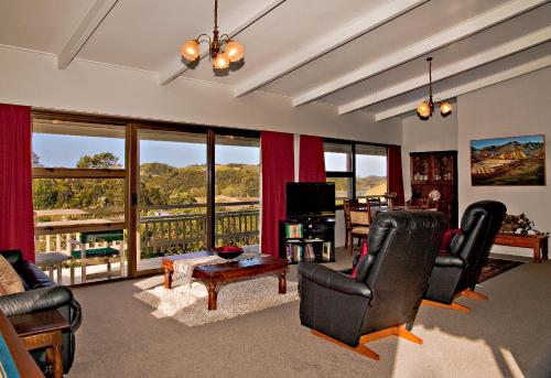 a living room with black chairs and a large window at High Tides in Ngunguru