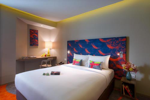 a bedroom with a large white bed with a painting on the wall at Tinidee Trendy Bangkok Khaosan in Bangkok