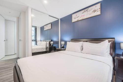 a bedroom with a white bed and a blue wall at Effortless Local Living on Greville Street in Melbourne