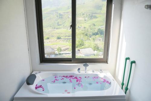 d'une baignoire avec une fenêtre fleurie. dans l'établissement En Hotel Sapa, à Sa Pa