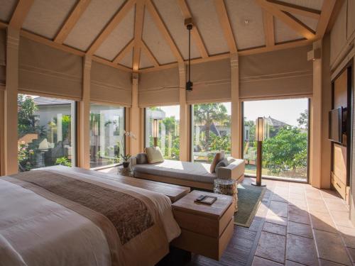 a bedroom with a large bed and large windows at The Ritz-Carlton Bali in Nusa Dua