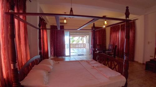 a bedroom with a canopy bed with red curtains at Blue pearl in Beruwala