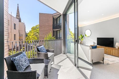 a balcony with chairs and a television on a building at The 249 Apartments by Urban Rest in Sydney