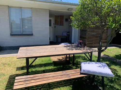 a wooden picnic table and a bench in a yard at Old fisherman's house on barkes - pet and family friendly in Lakes Entrance