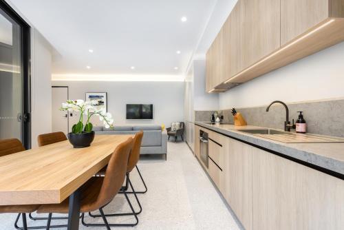 雪梨的住宿－The 249 Apartments by Urban Rest，厨房以及带木桌的用餐室。