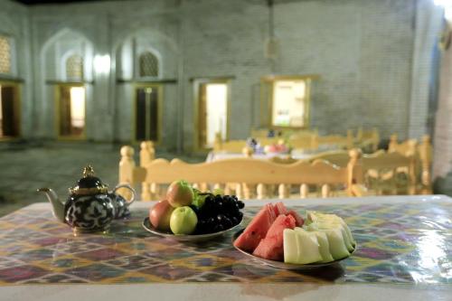 uma mesa com dois pratos de fruta numa mesa em Karavansaray Xurjin Old em Bukhara