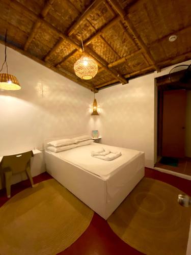a bedroom with a white bed and a chair at Kasa Raya Inn in Tibiao