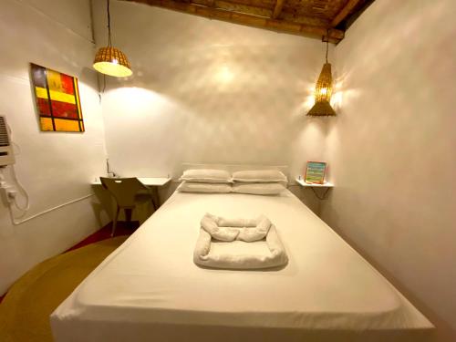 Cama blanca en habitación con 2 luces en Kasa Raya Inn, en Tibiao