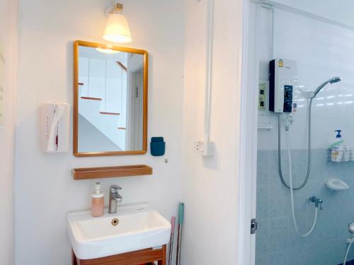 een badkamer met een wastafel, een spiegel en een douche bij Room Story Hostel in Phra Nakhon Si Ayutthaya