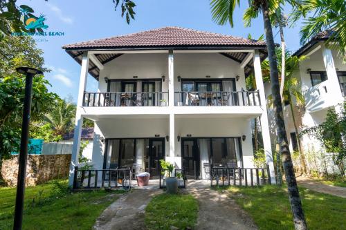 a white house with a balcony and palm trees at Koh Rong Hill Beach Resort in Koh Rong Island