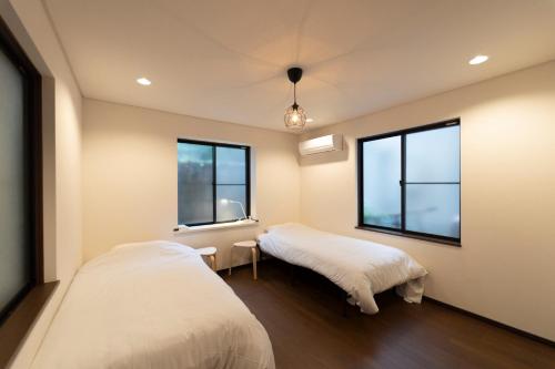 two beds in a room with two windows at SATELLITE HOTEL Roppongi サテライトホテル六本木 in Tokyo