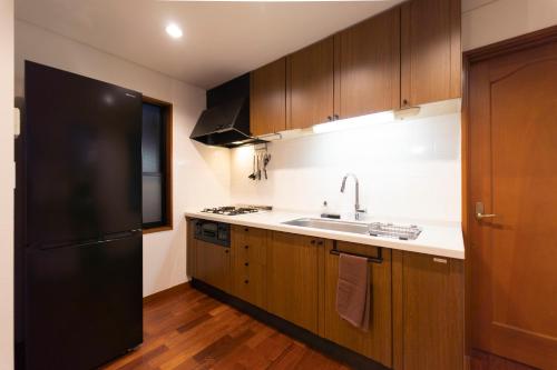 eine Küche mit einem schwarzen Kühlschrank und einer Spüle in der Unterkunft サテライトホテル六本木/Satellite Hotel Roppongi in Tokio