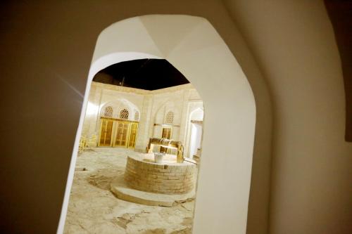 um arco que leva a um quarto com casa de banho em Karavansaray Xurjin Old em Bukhara