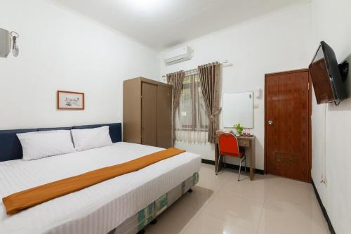um quarto com uma cama, uma secretária e uma televisão em House of M Bogor Mitra RedDoorz em Bantarkamang